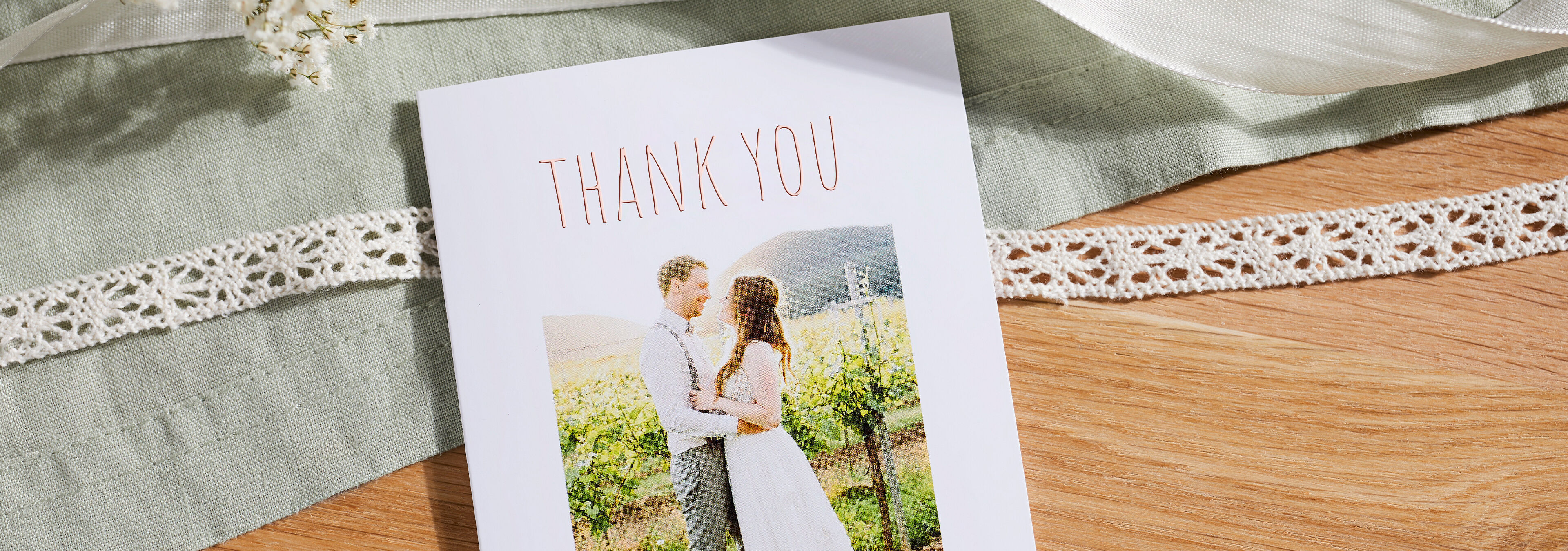 An elegant thank you card with a bride and groom in front of vineyards.