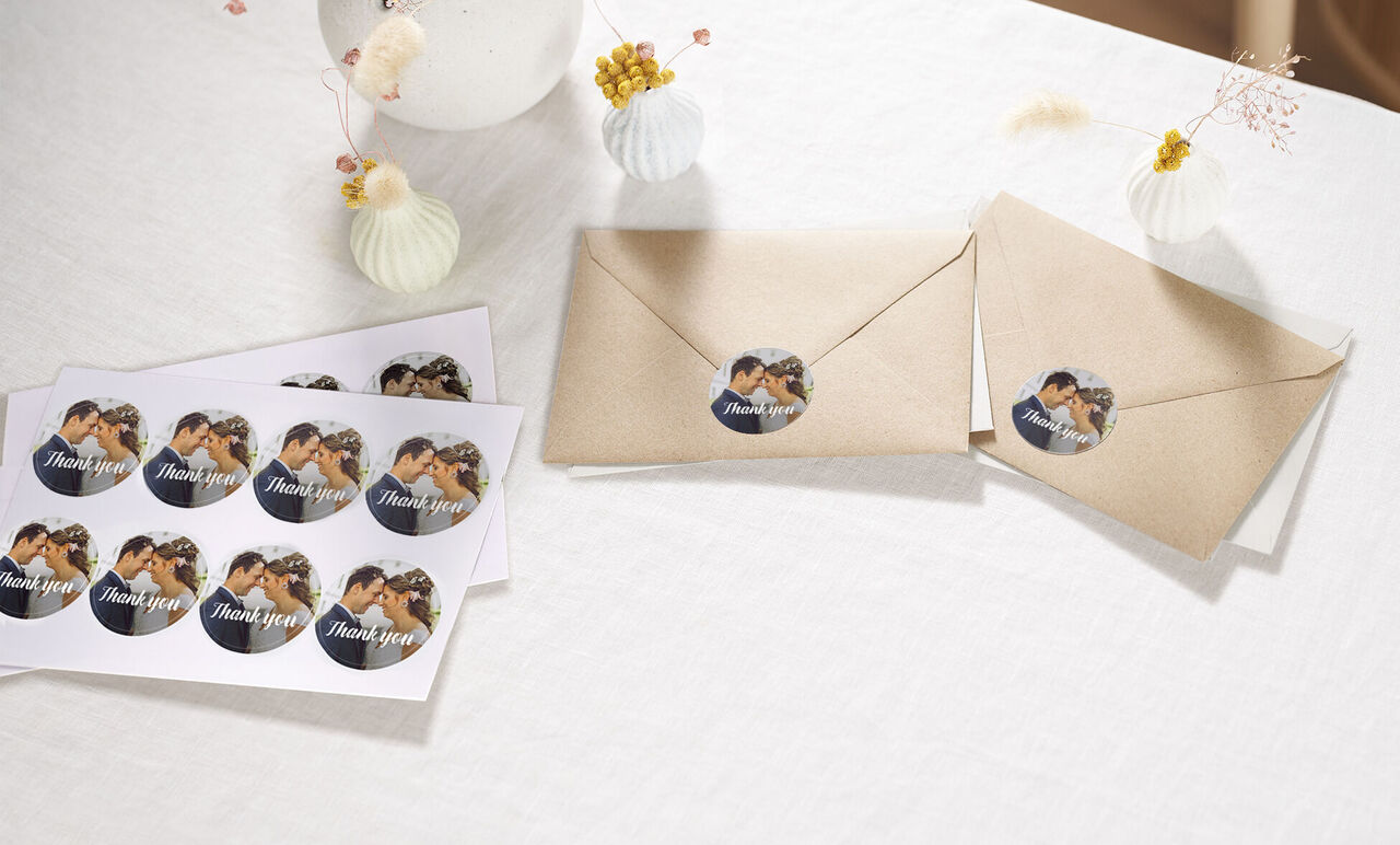 Two brown envelopes with round thank you stickers and stamped cards on a table.
