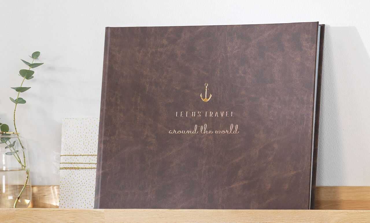 A high-quality photo book titled 'Jeremy's Travel around the world' in brown leather design on a shelf.