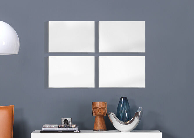 Empty white frames on a gray wall, decorated with stylish vases and a camera.