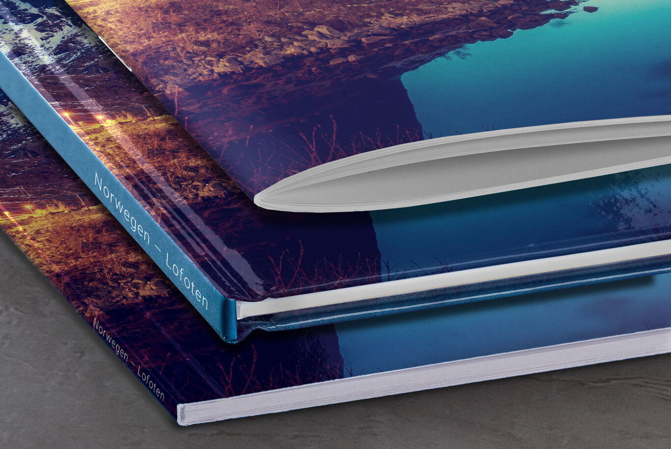 Three CEWE PHOTO BOOKS can be seen stacked, each showing an extraordinary cover design inspired by Norwegian landscapes.