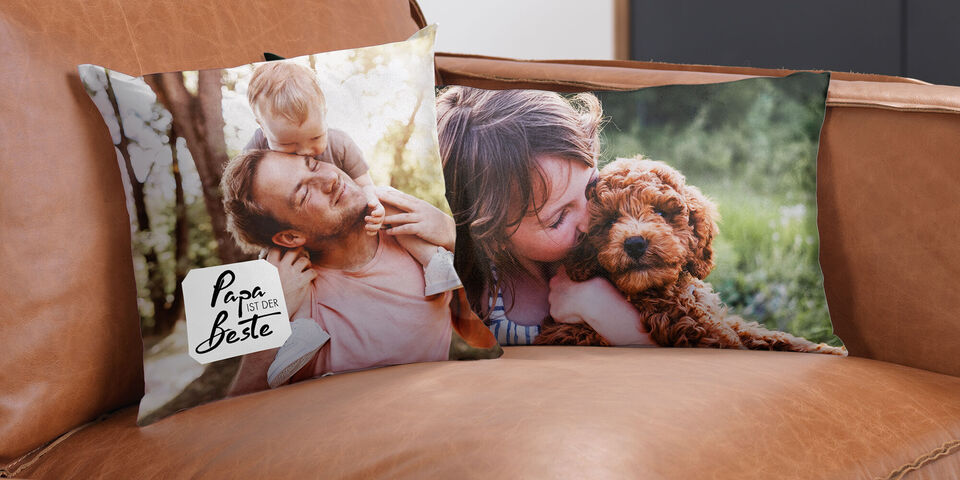 Two personalized pillows on a leather sofa. One shows a father with his child and the other a woman cuddling a dog.