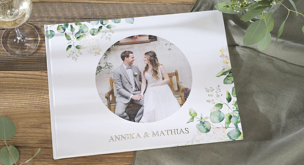 A beautiful CEWE PHOTOBOOK featuring a bride and groom. They sit in a cozy room, radiating happiness.