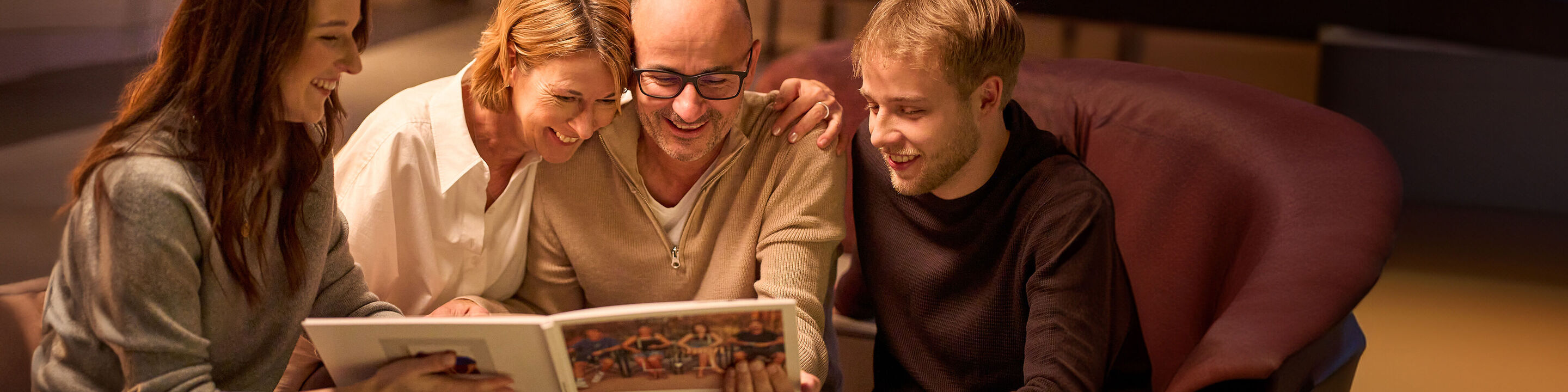 Family looks at a CEWE photo book showing beautiful memories.