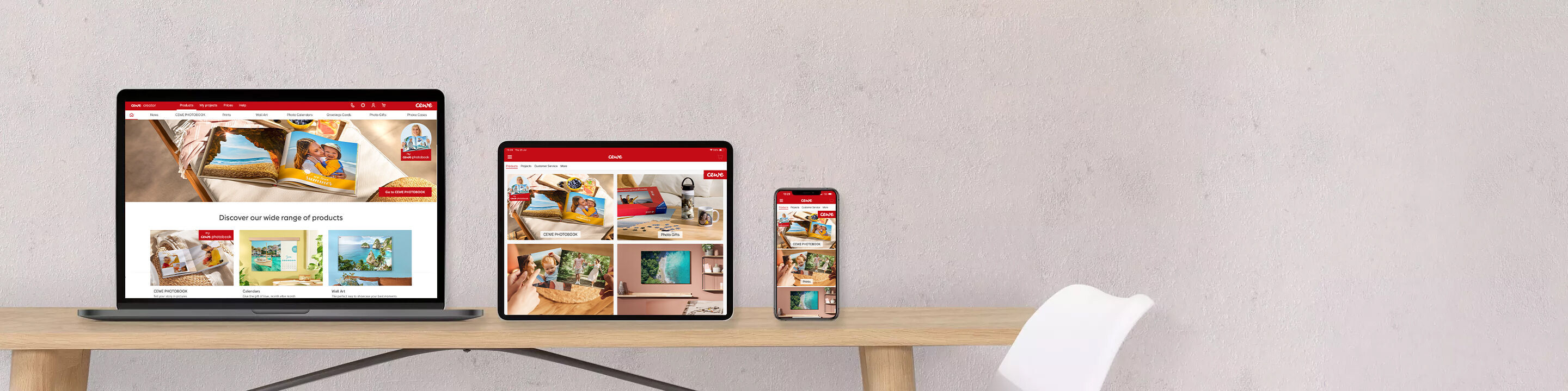 Three different devices showing the CEWE website with photo products and happy moments.