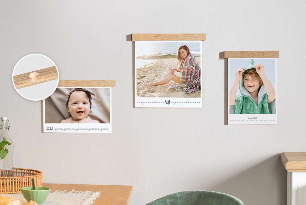 Three photo calendars with wooden elements on the wall, one shows a person at the beach, another a child with a towel.