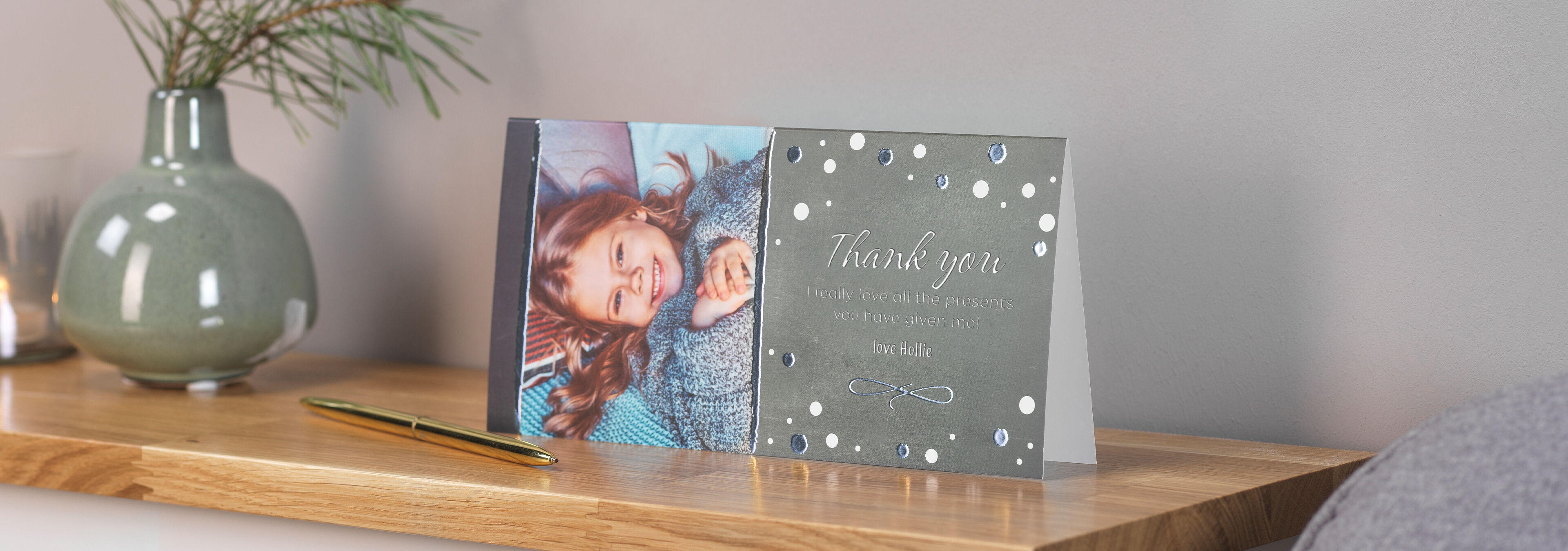 A lovingly designed CEWE greeting card with a photo of a smiling girl, placed on a wooden table.