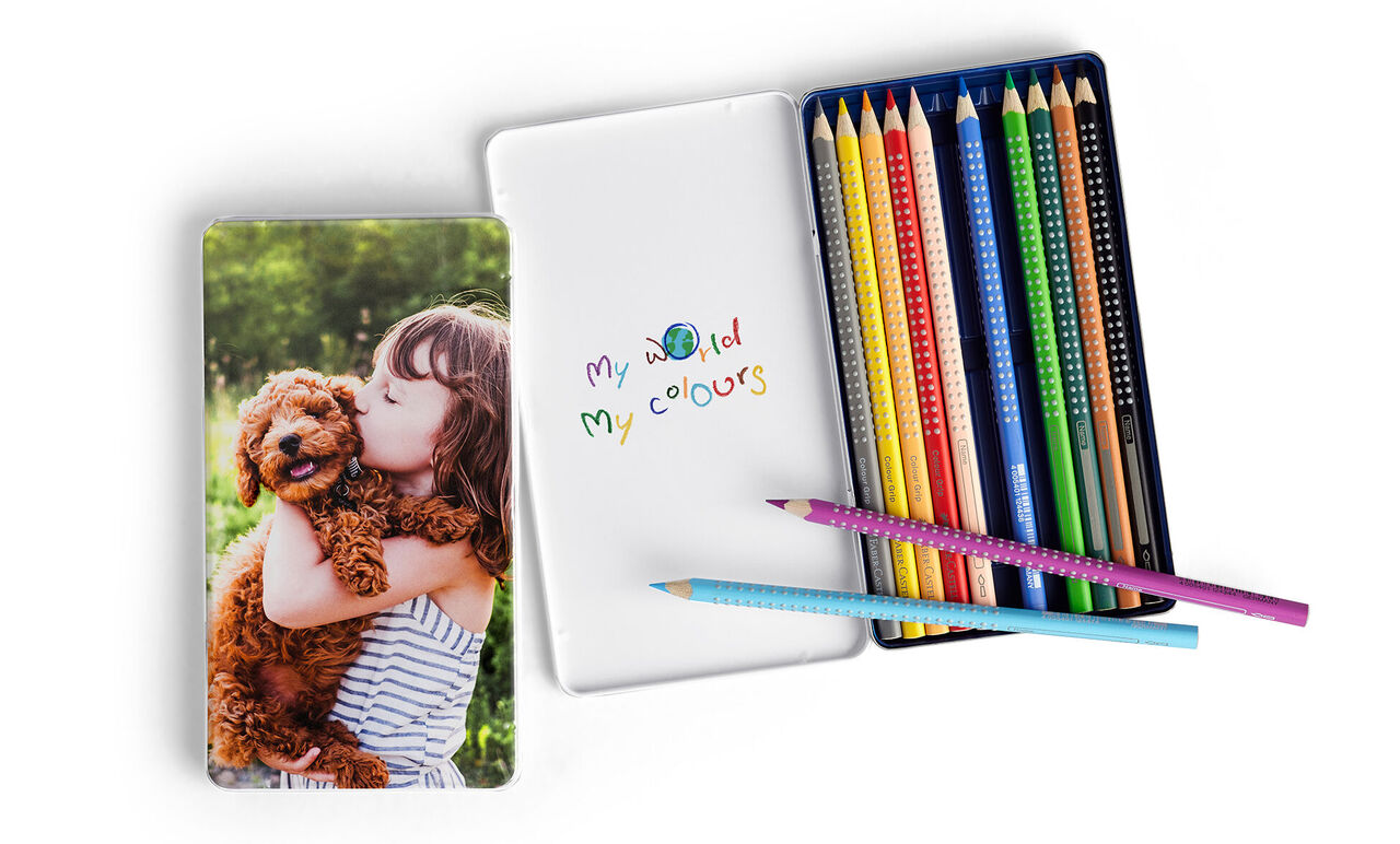 A cheerful child hugs a dog on a notebook, colorful colored pencils beside them