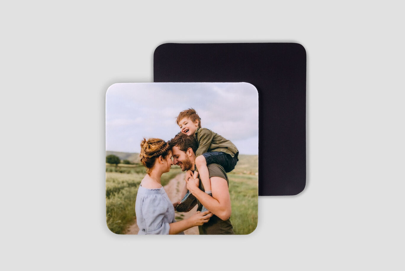 A family enjoying a sunny moment outdoors with a child on the father's shoulders.