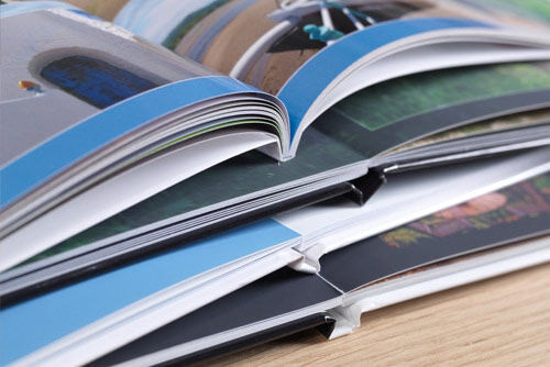 Open CEWE PHOTO BOOK displays colorful pages with photos and designs.