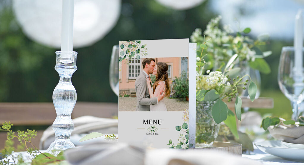 A beautiful wedding menu on an elegant table with flowers and candles.