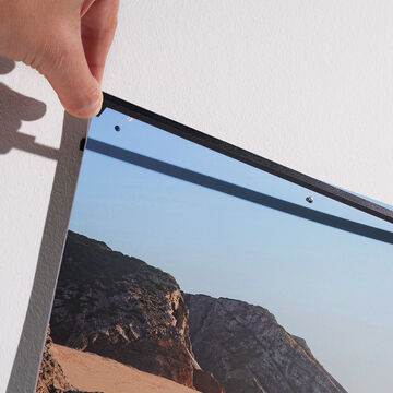 A person hangs a beautiful wall picture featuring a landscape motif