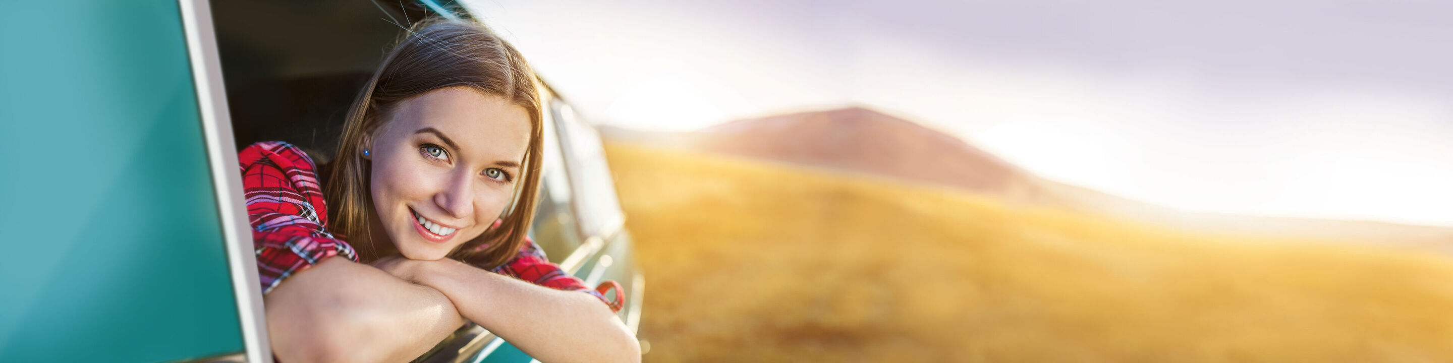 A person leans relaxed out of a vehicle window enjoying the beautiful scenery.