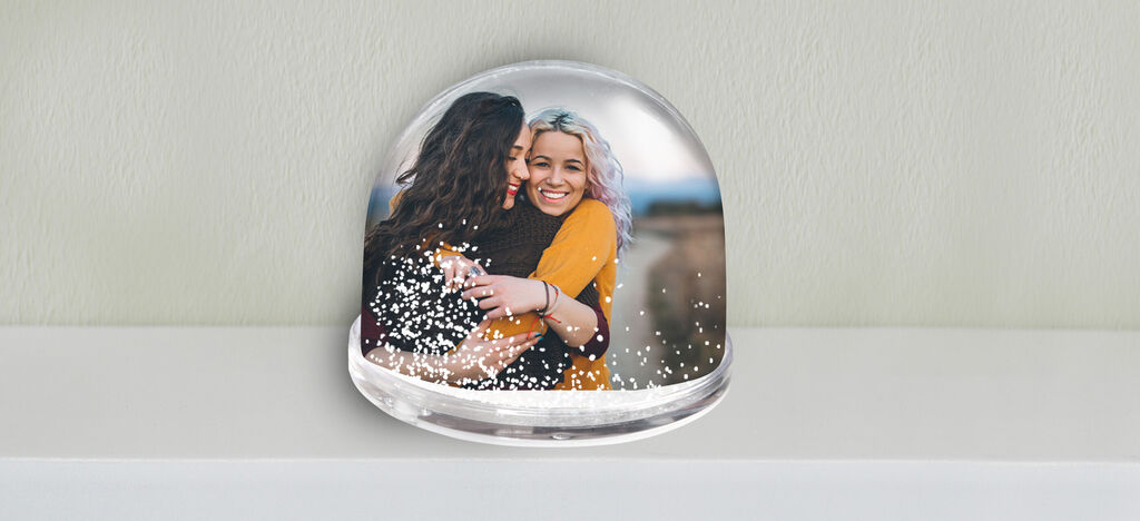 Two people embrace in a snow globe.