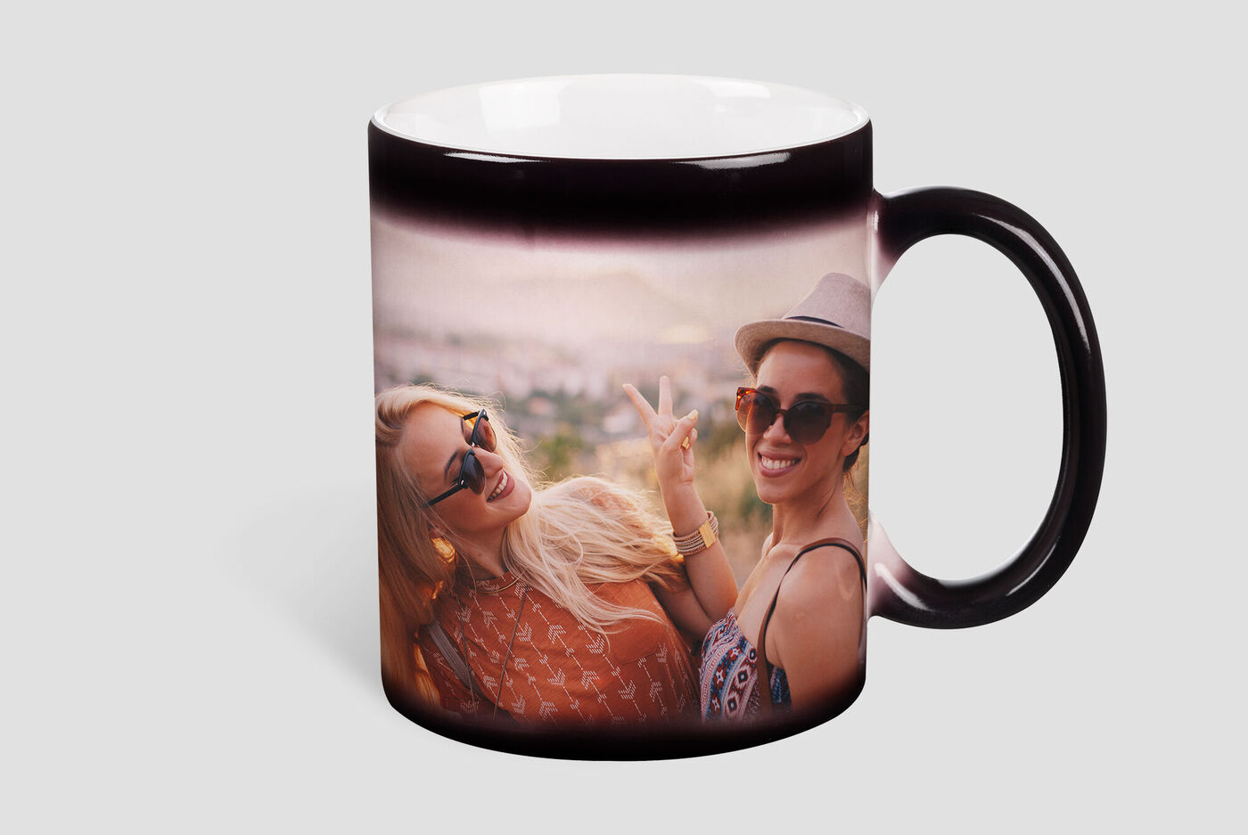 Two cheerful women enjoy a moment of joy while drinking from a cup.