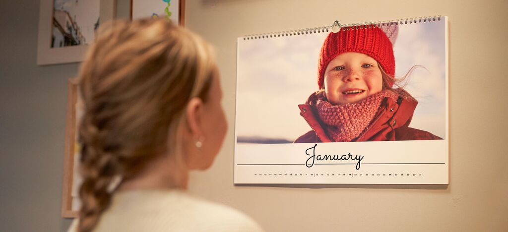 A person looks at a calendar featuring a photo and the words "January."
