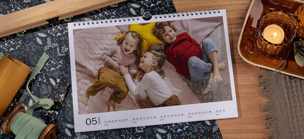 Three children lie relaxed on a cozy bed surrounded by pillows and a blanket.