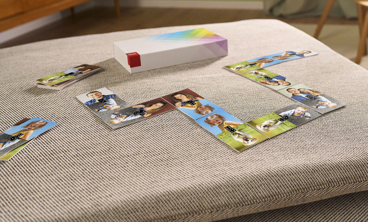 Stacked photo book with image cards on a table, surrounded by photos of people and pets.