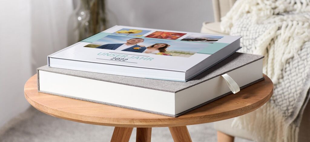 Two CEWE PHOTO BOOKS on a wooden stand, one slightly open.
