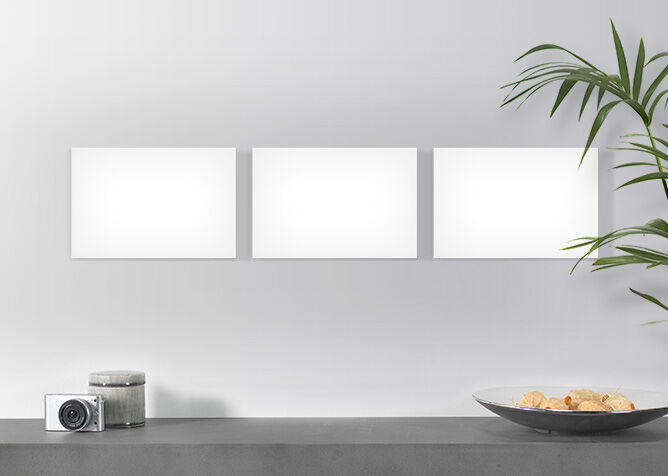 Three empty picture frames on a wall over a table with a bowl of snacks and a camera.