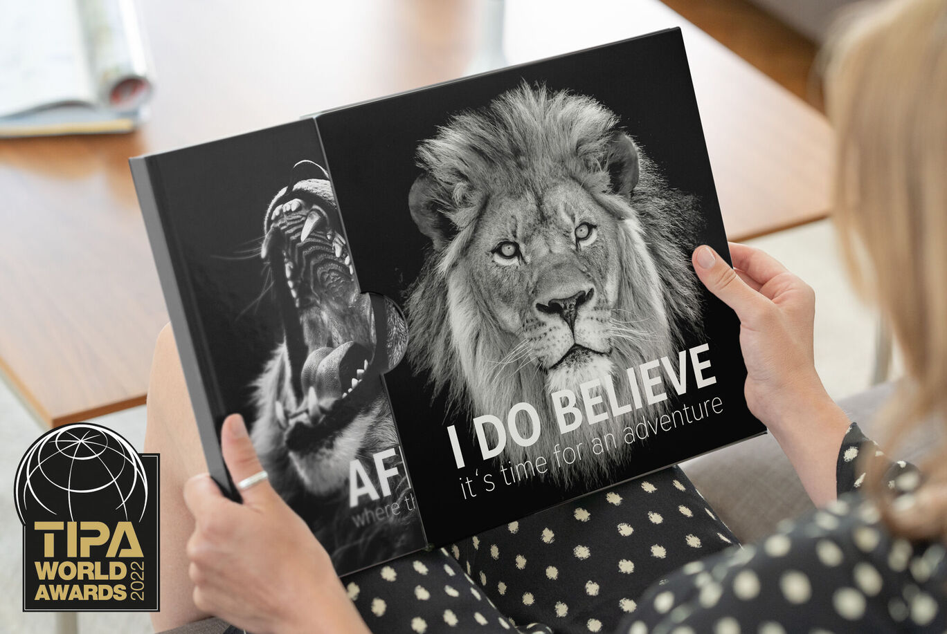 Woman holding a CEWE photo book with a lion on the cover and an impressive gorilla illustration.