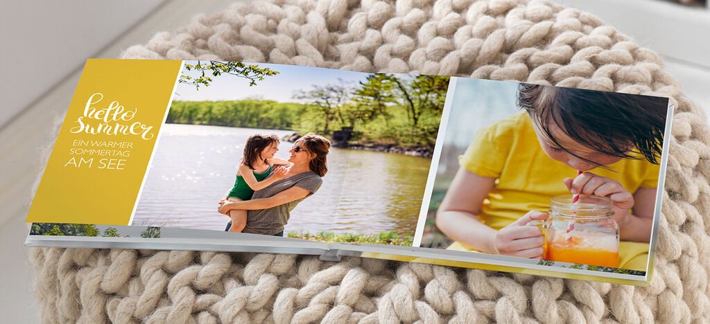 A mother kisses her daughter by the lake while a boy drinks juice.