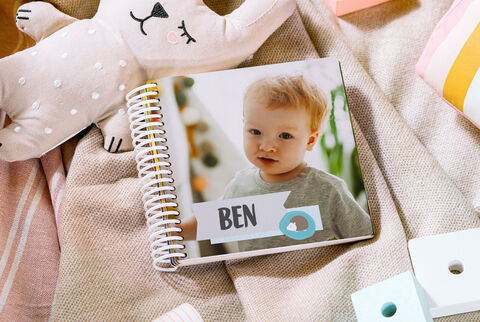 A CEWE photo book named Ben on the cover, surrounded by plush toys and colorful toys.