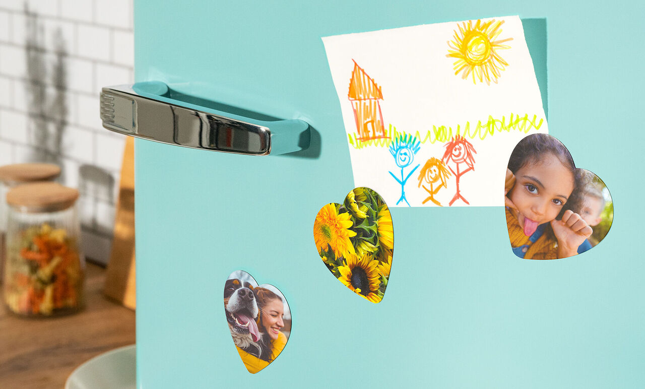 Colorful magnets hold photos and a drawing on a blue refrigerator.