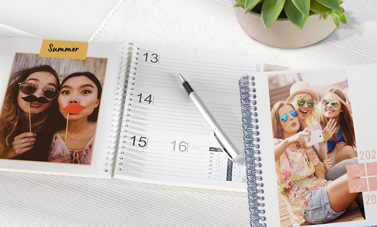 A planner, a photo page, and a plant on a table.