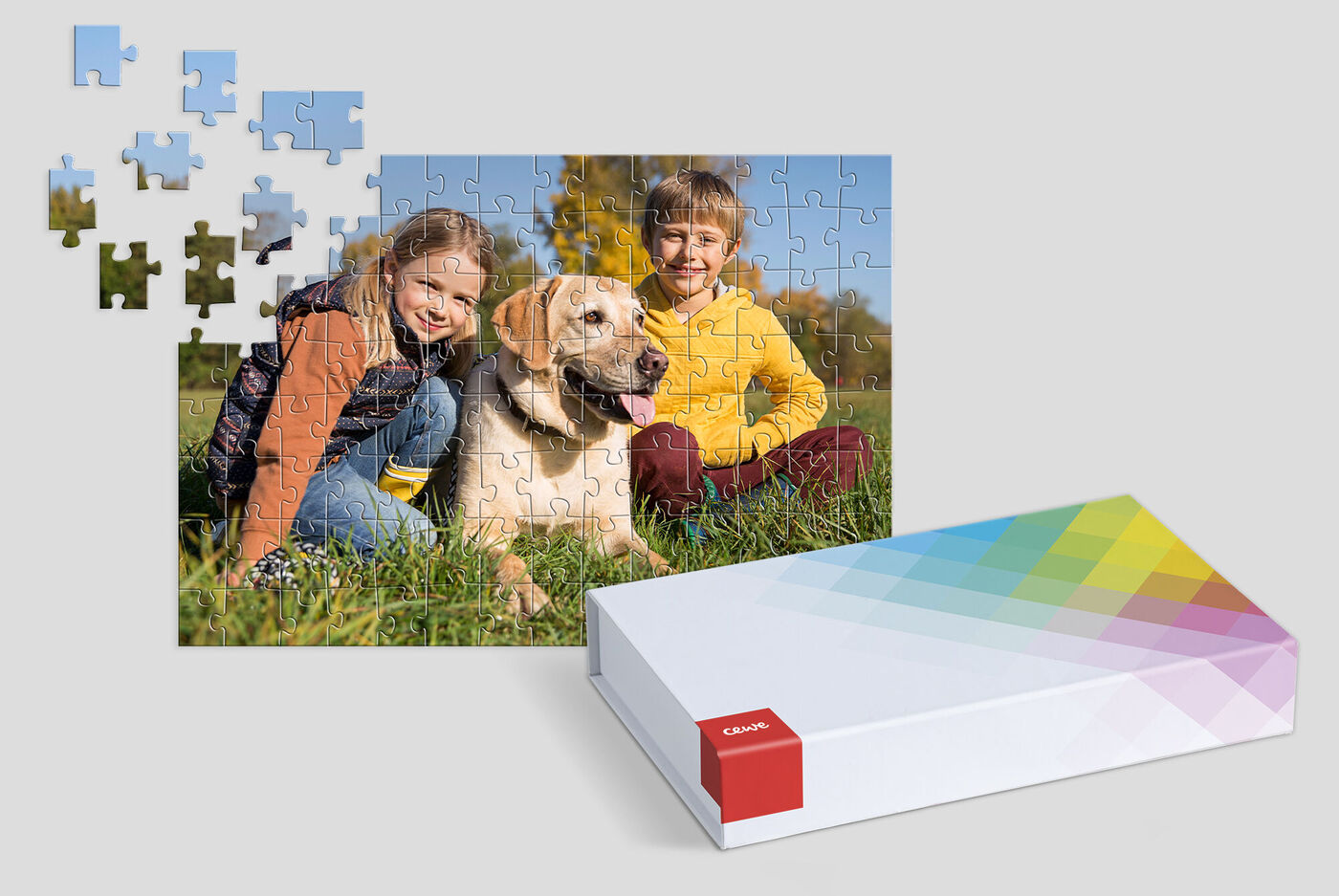 A dog with two children sits on a meadow while puzzle pieces are scattered around them