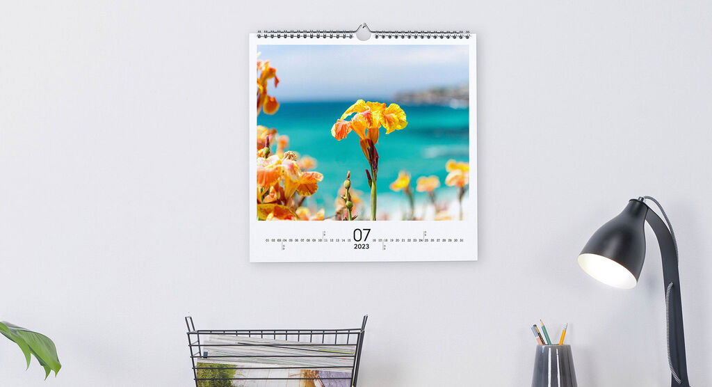 A beautiful wall calendar featuring a picture of bright yellow flowers against a blue water horizon.