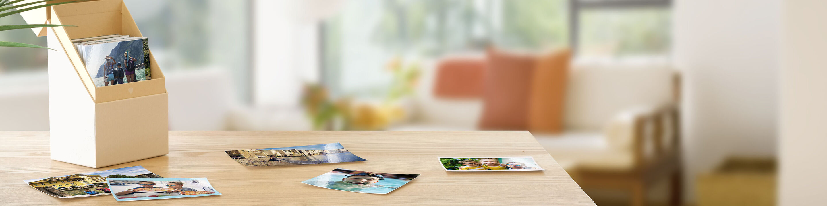 A wooden stand with photos and postcards on a table. Background shows a room with sofa and plants.