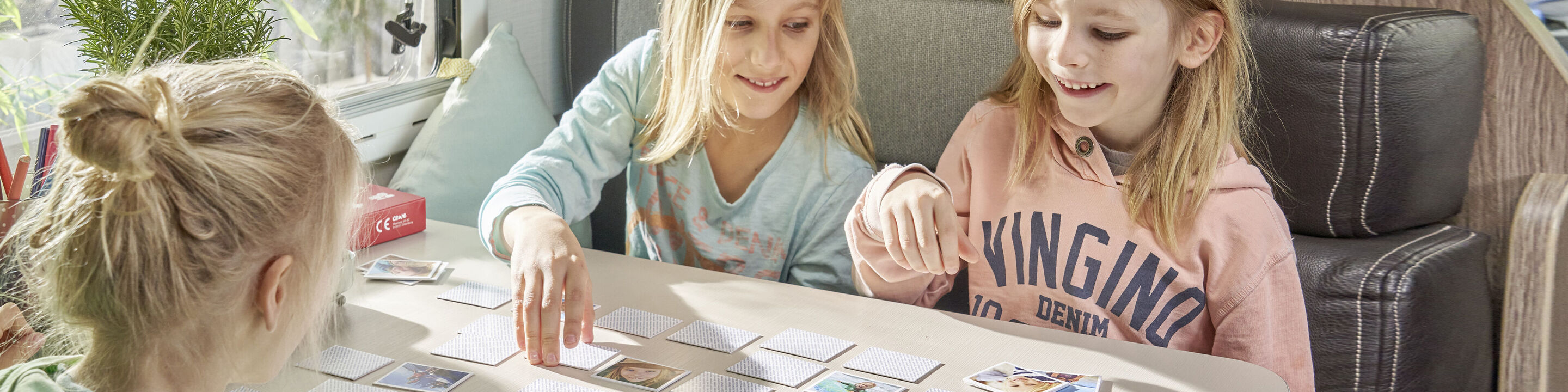 Children play a card game at the table and laugh