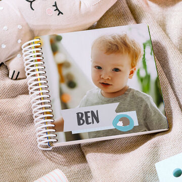 An open CEWE photo book named Ben. The book lies on a cozy surface.