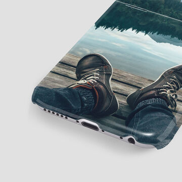 A pair of feet in shoes looking over a lake - a relaxing time by the water.