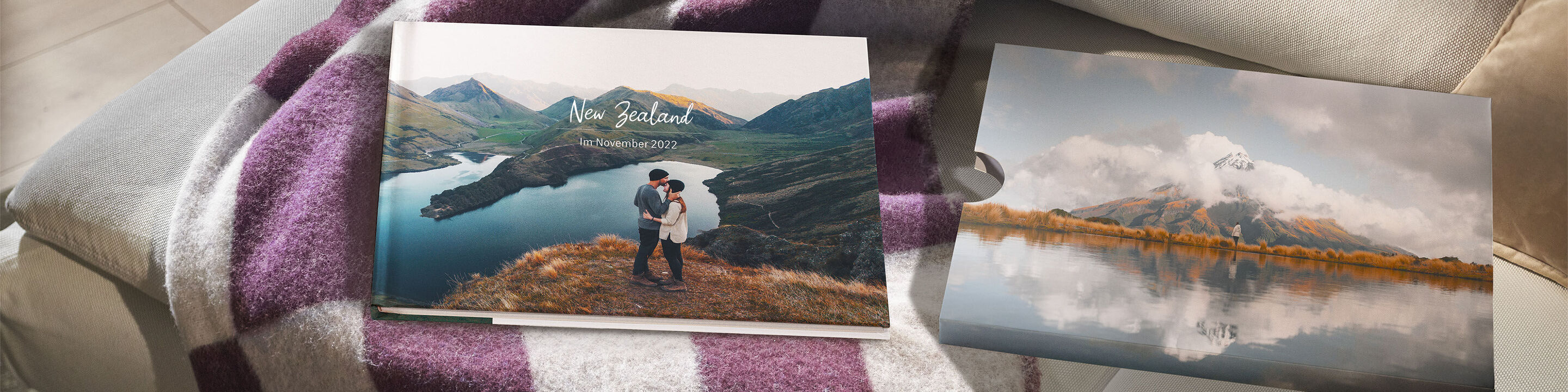 Two CEWE photo books on a table with landscape images.