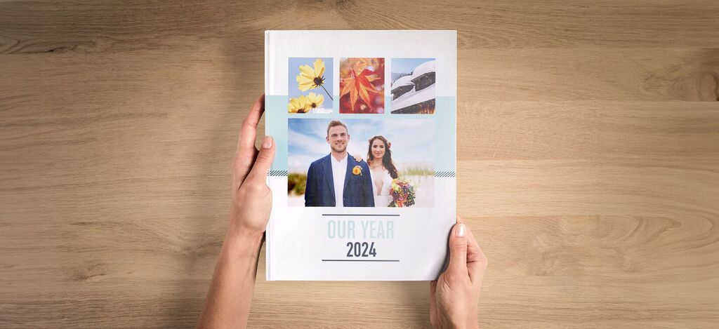 A person holds a photo book with images and a title in the center.