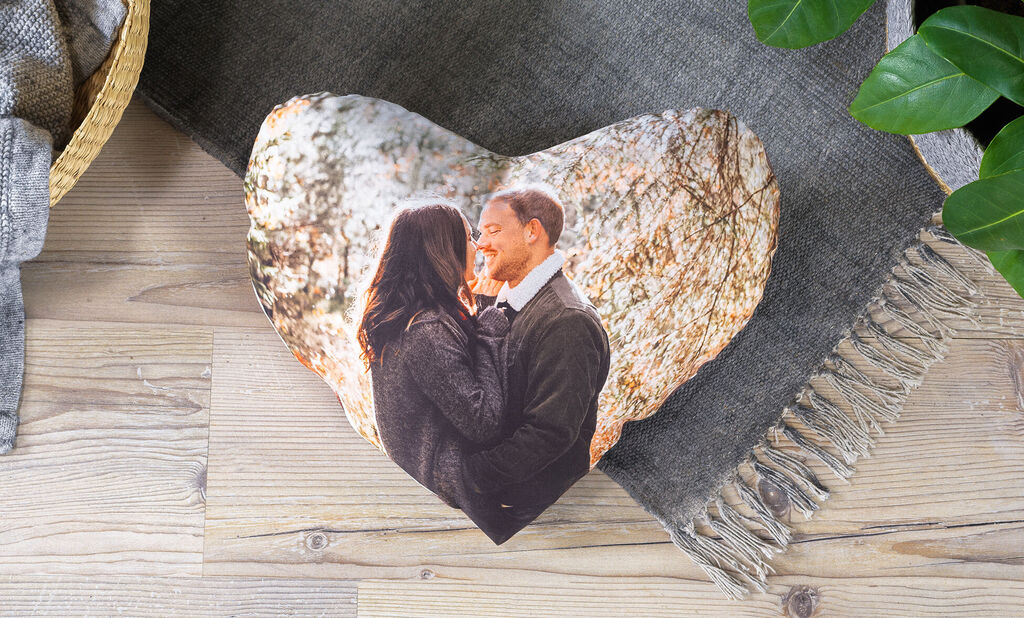 Heart-shaped pillow with a couple in nature in the background.