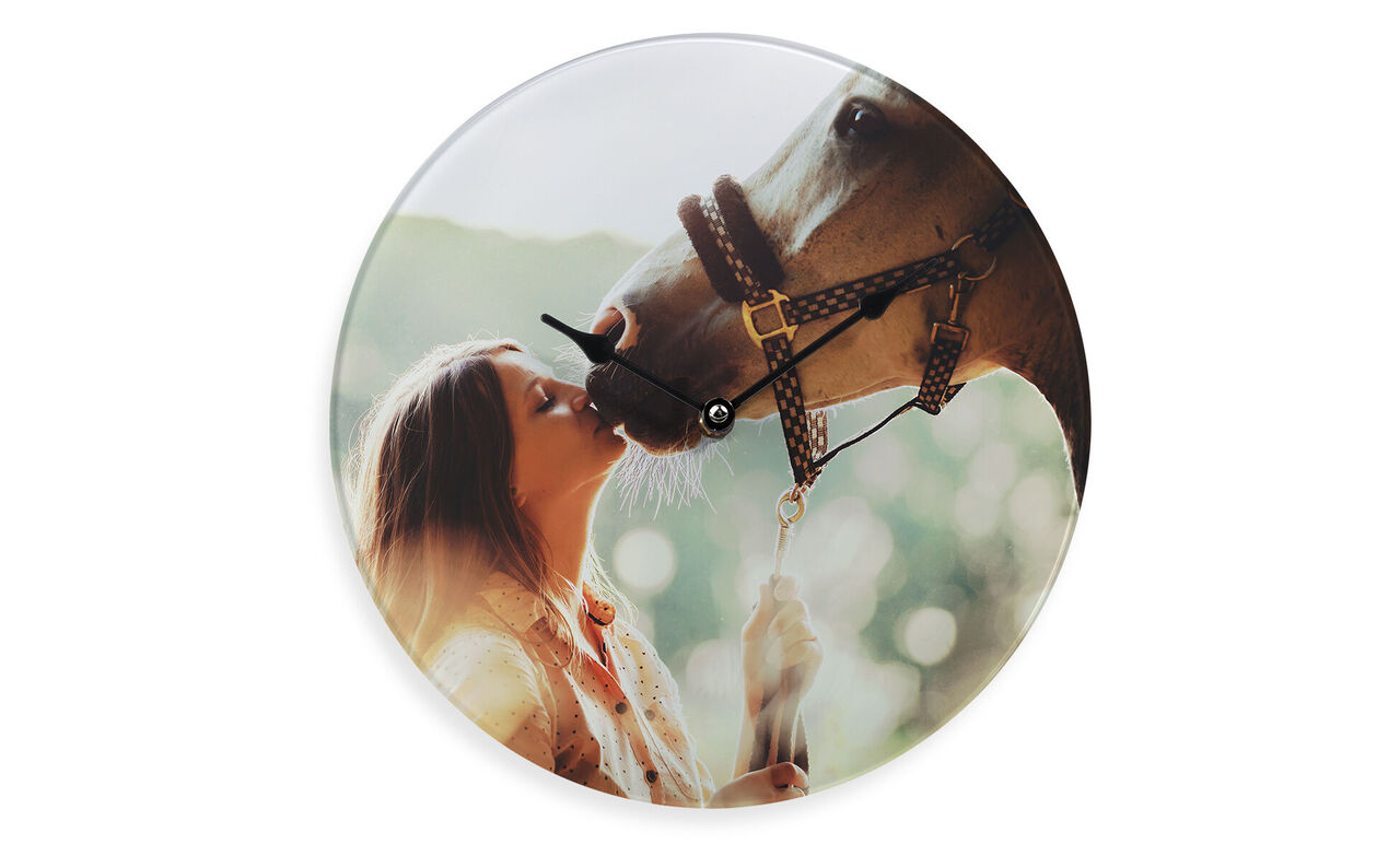 A woman lovingly kisses a horse on its snout against a dreamy natural backdrop.
