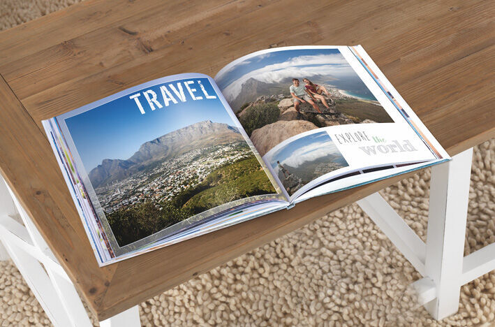 An open CEWE PHOTO BOOK with travel images on a table.