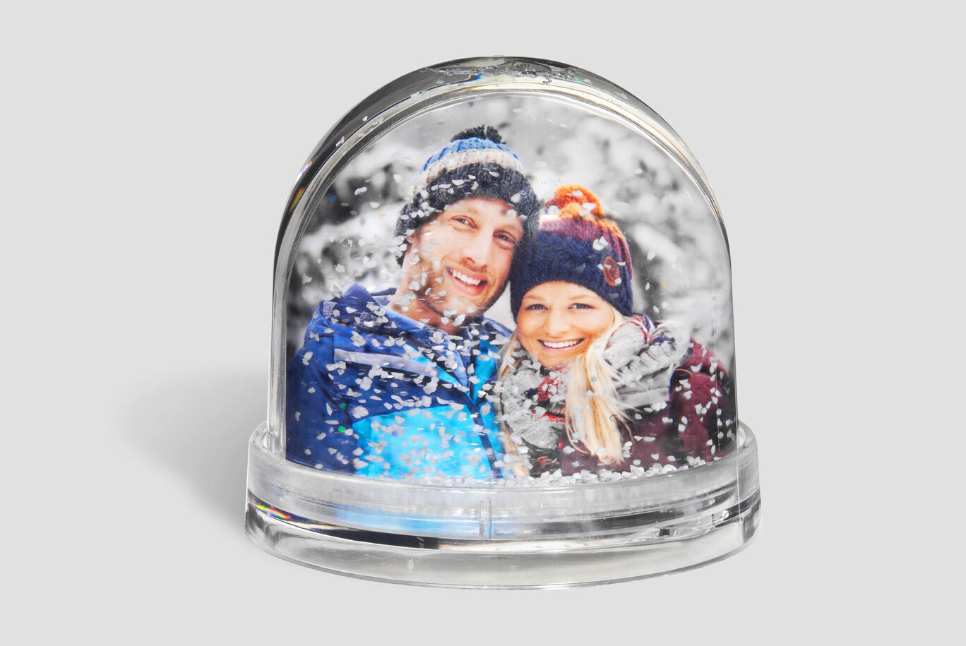 Two people in a snow globe surrounded by snowflakes
