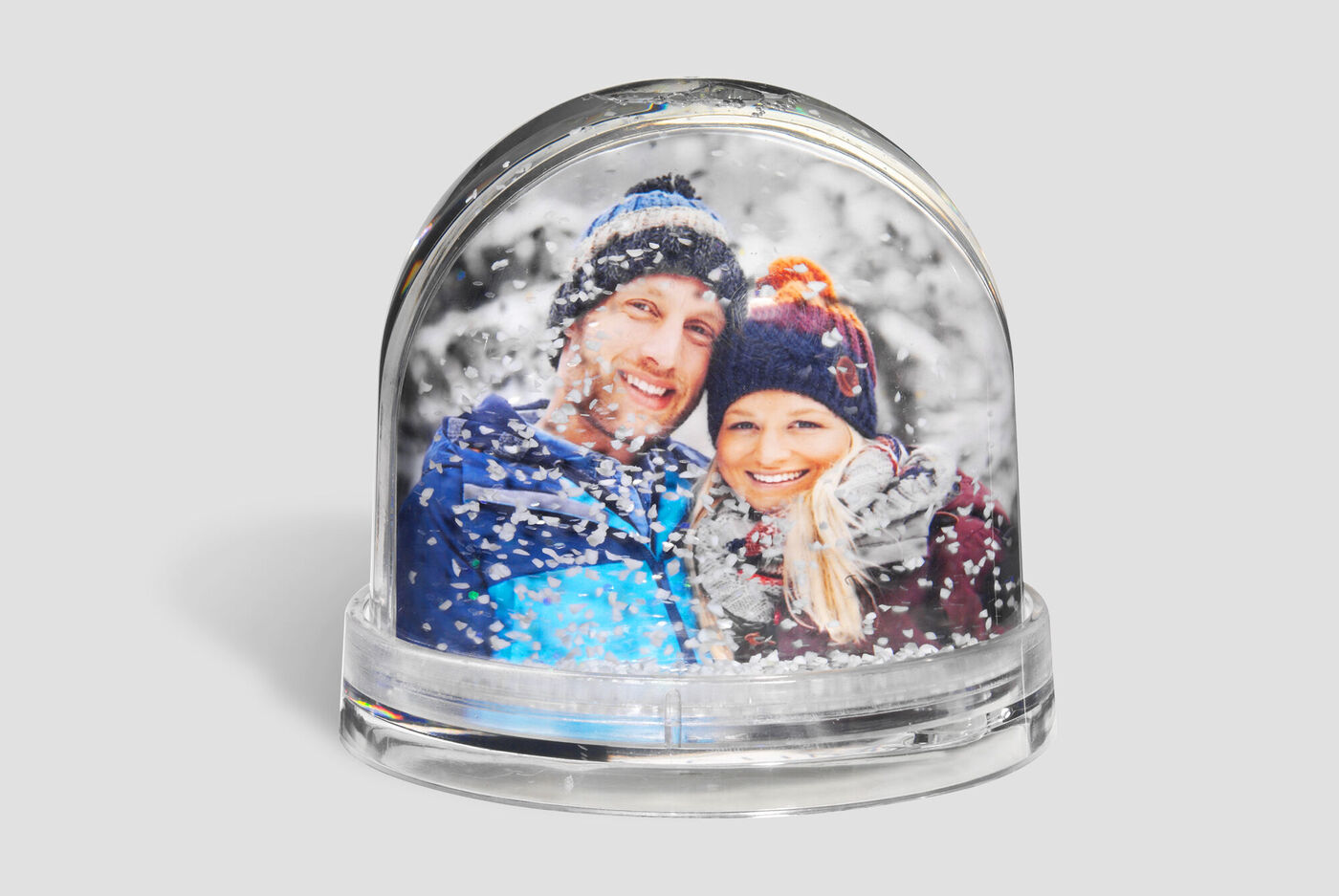Two people in a snow globe surrounded by snowflakes