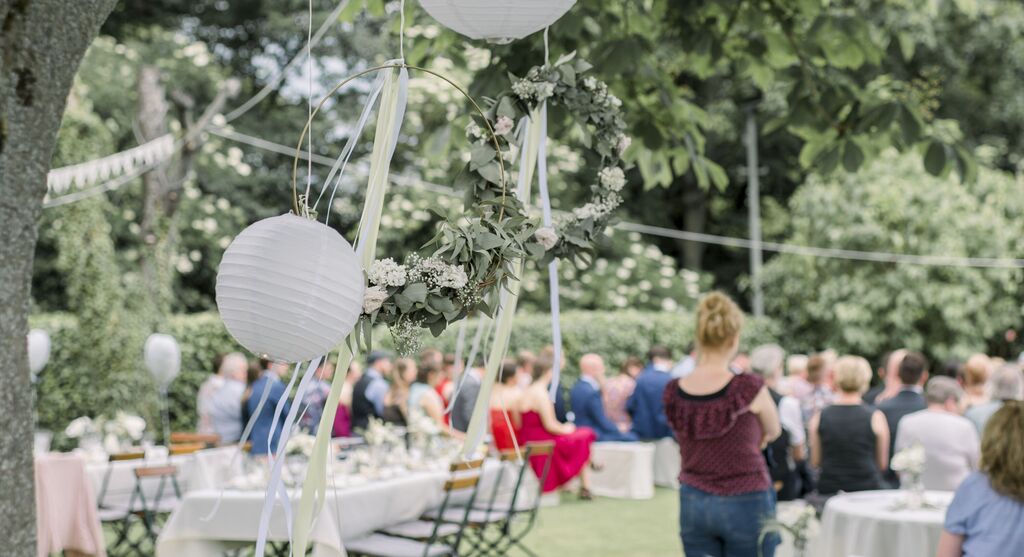 Wedding celebration in the garden with decorative lanterns and floral wreaths.