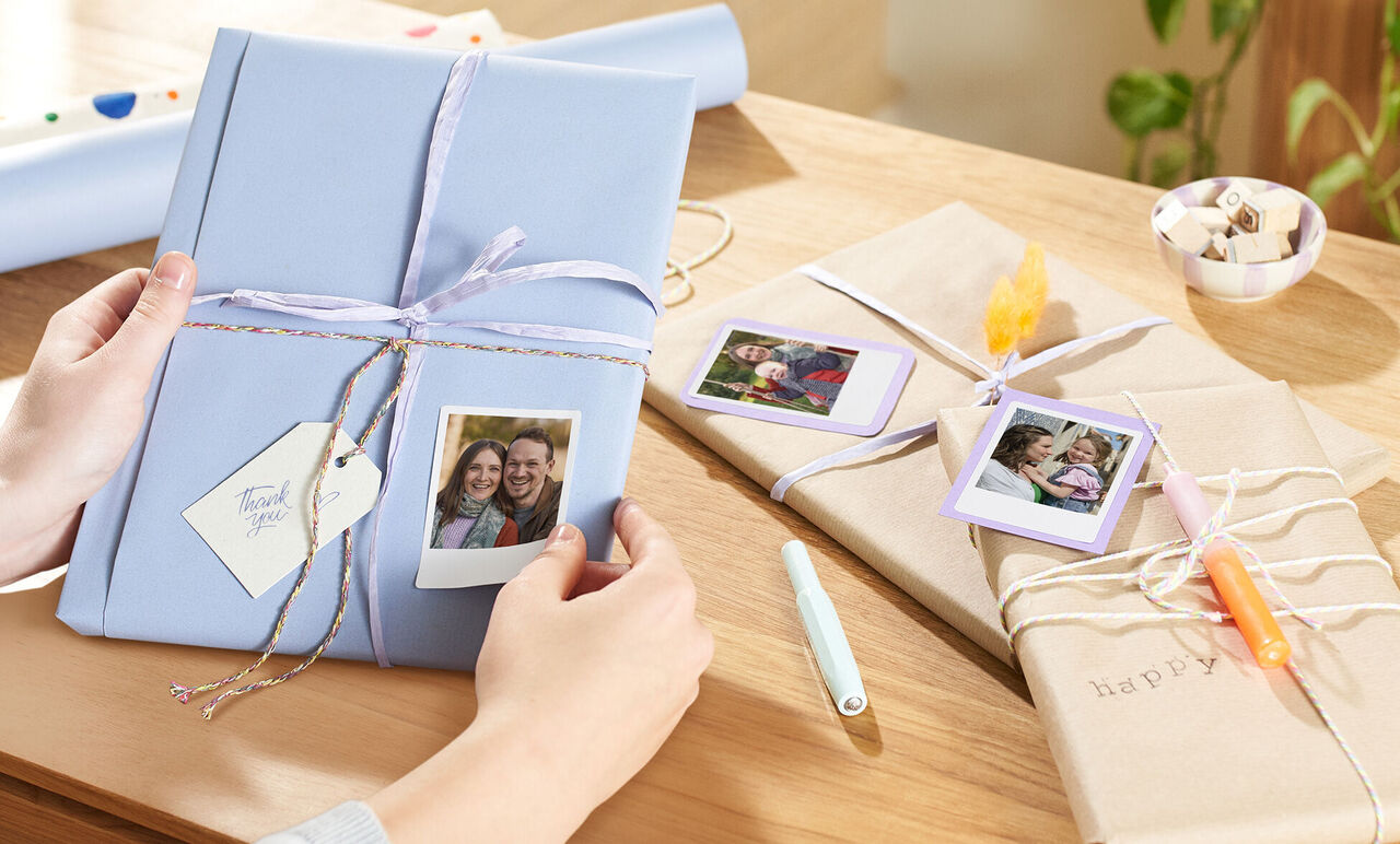 Two beautifully wrapped gifts on a table with pictures and decorative ribbons.