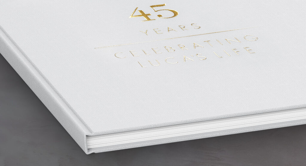 A white photo book with golden embossing for a 45th birthday reported by CEWE PHOTO BOOK.