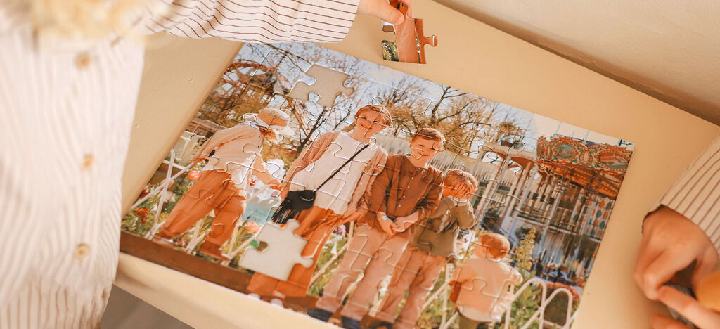 A group of 4 children smile while working on a puzzle, with a fair in the background.