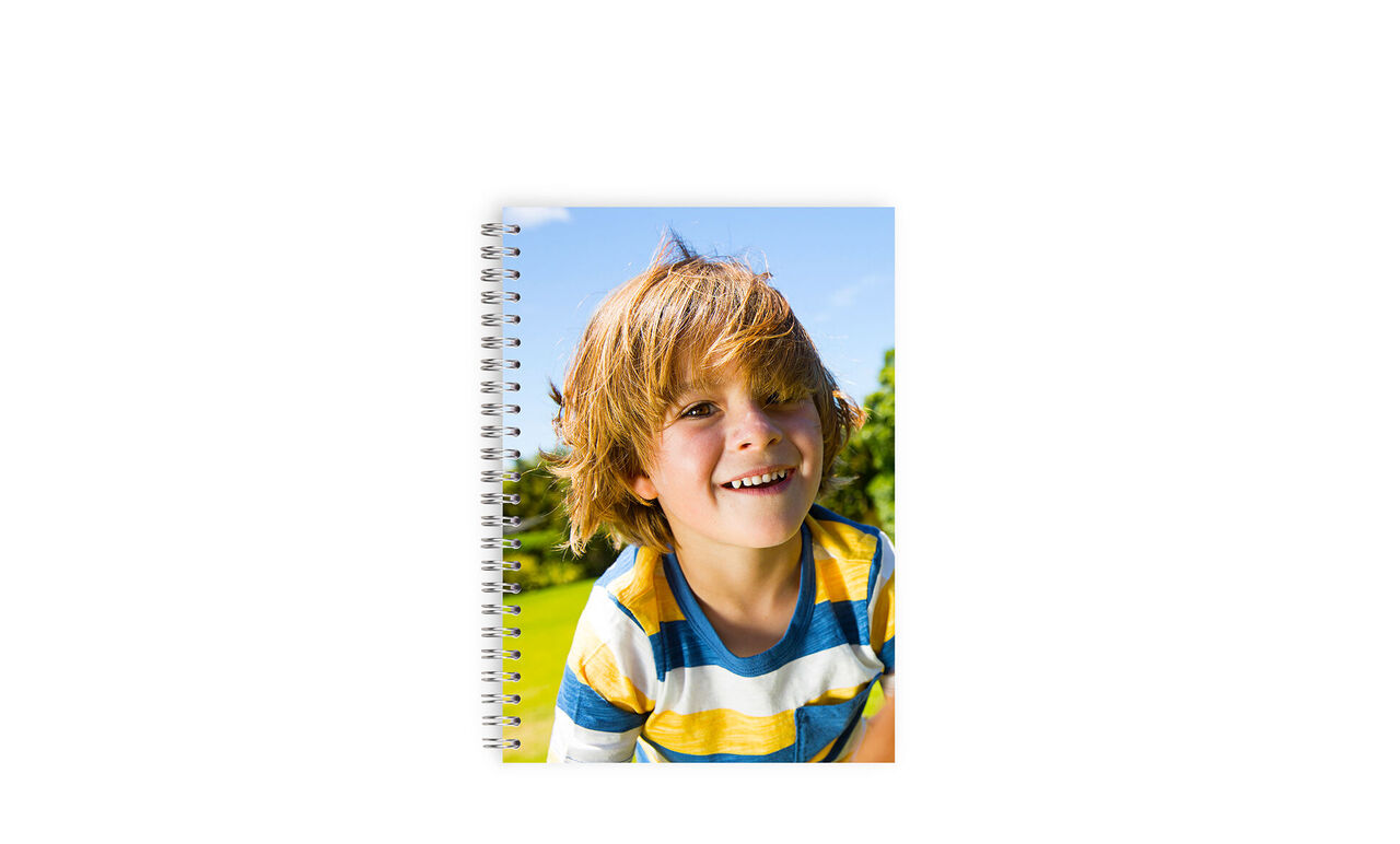 Happy child with a personalized notebook in hand, surrounded by nature.