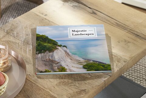 An open photo book with landscape images on a wooden table.