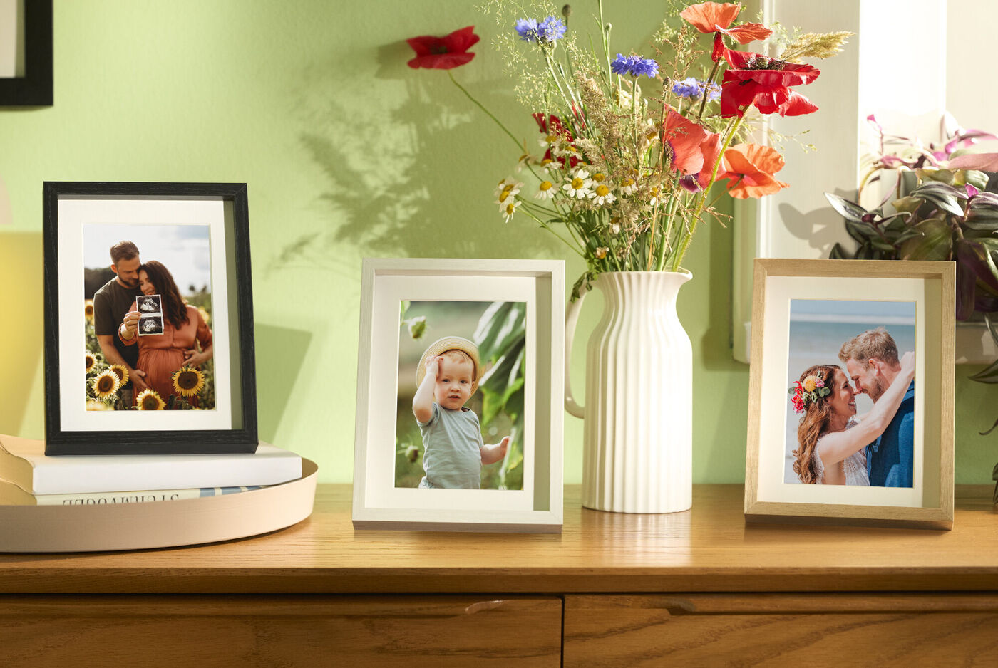 Three beautifully framed photos on a table showing love and happy moments.