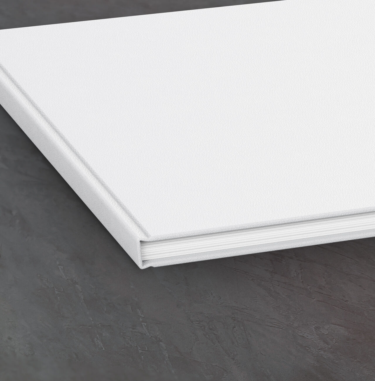 A closed, white photo book near a dark surface.